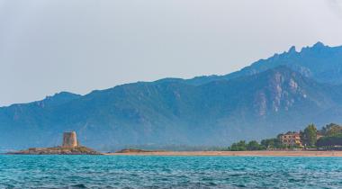 Torre costiera e montagne, mare blu, atmosfera serena e maestosa.
