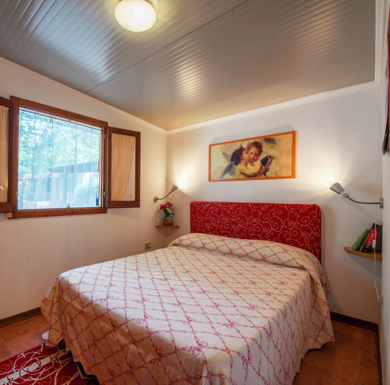 Camera da letto accogliente con letto matrimoniale, finestre luminose e decorazioni semplici.